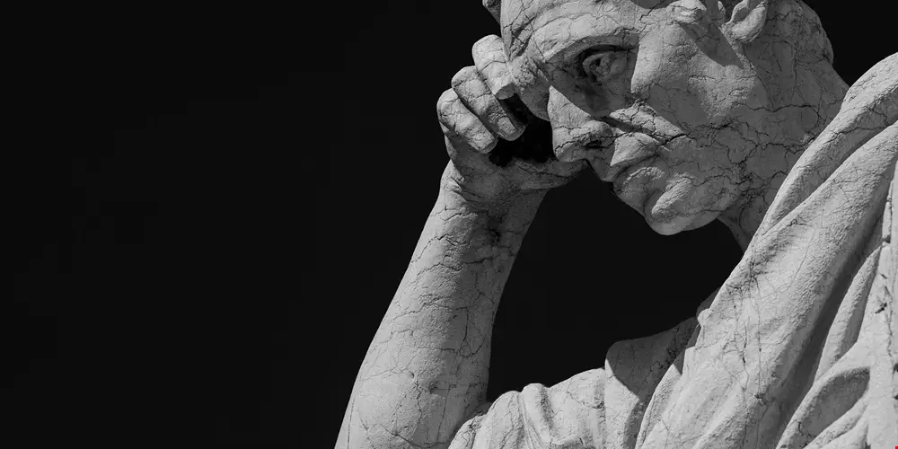 Skulptur av Auguste Rodin föreställande en skäggig man som är djupt försjunken i tankar. Statyn kallas för Tänkaren.