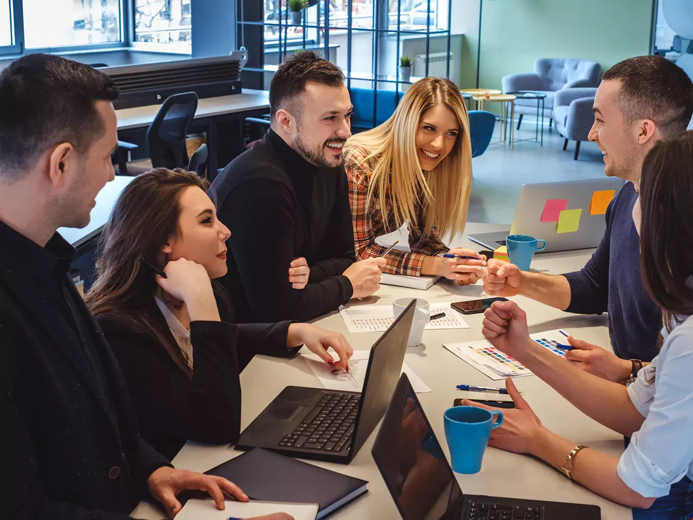 En grupp medarbetare runt ett konferensbord, kreativt möte, ser ut att trivas